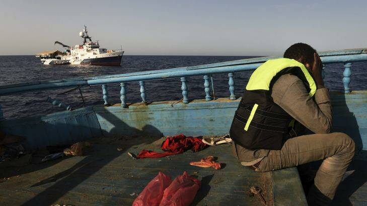 A refugee sits in despair on a wooden fishing boat as he waits to be rescued off the coast of Libya.  Photo: Kate Geraghty