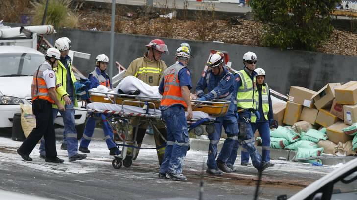 Rescue workers carry away one of the people trapped under the truck. Photo: Peter Rae