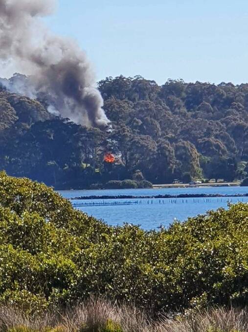 Pictured from across the Moruya River, Beryl Brierley's home goes up in flames. Image: Supplied. 