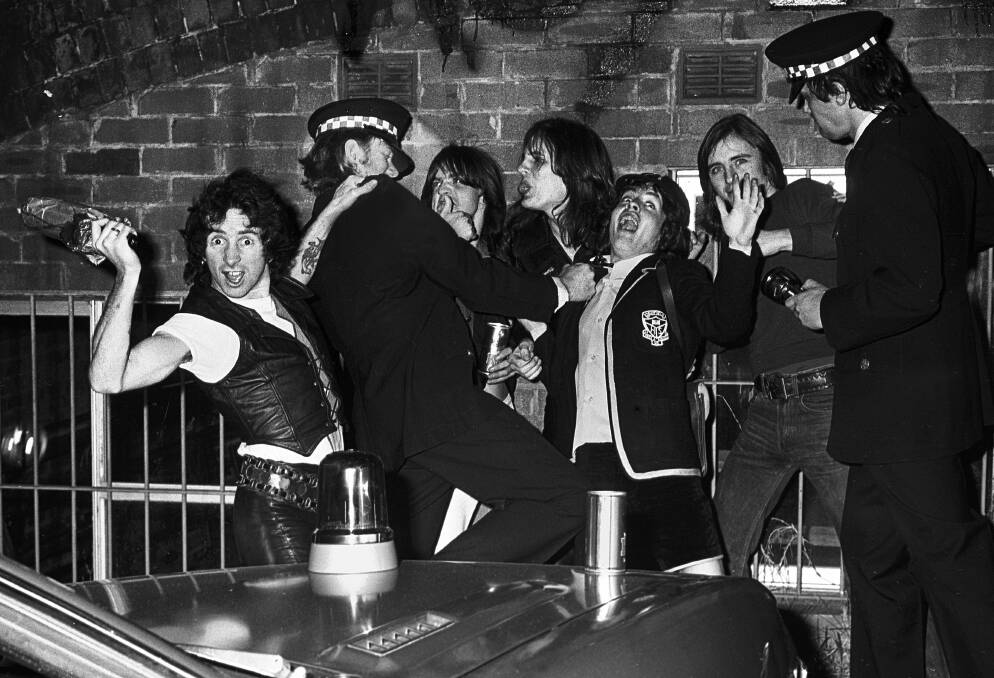 AC/DC and their roadies (in police uniforms), mess about for the camera. Picture: Philip Morris