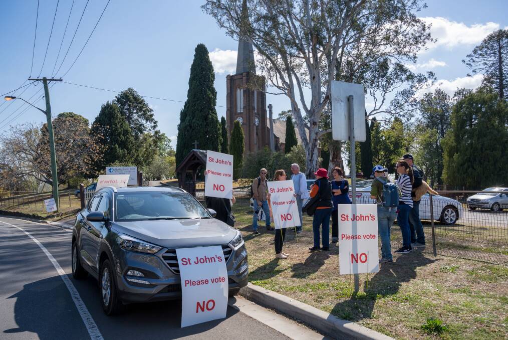 Passive protest: Anti-sale advocates hold signs outside the church before services on Sunday. Picture: Brett Atkins