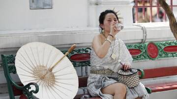 A tourist drinks water during hot weather at the Temple of Dawn or Wat Arun in Bangkok. (EPA PHOTO)